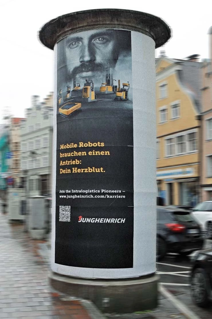 Zu sehen ist ein großes Plakat von jungeheinrich an einer großen Werbesäule in einer Stadt.
