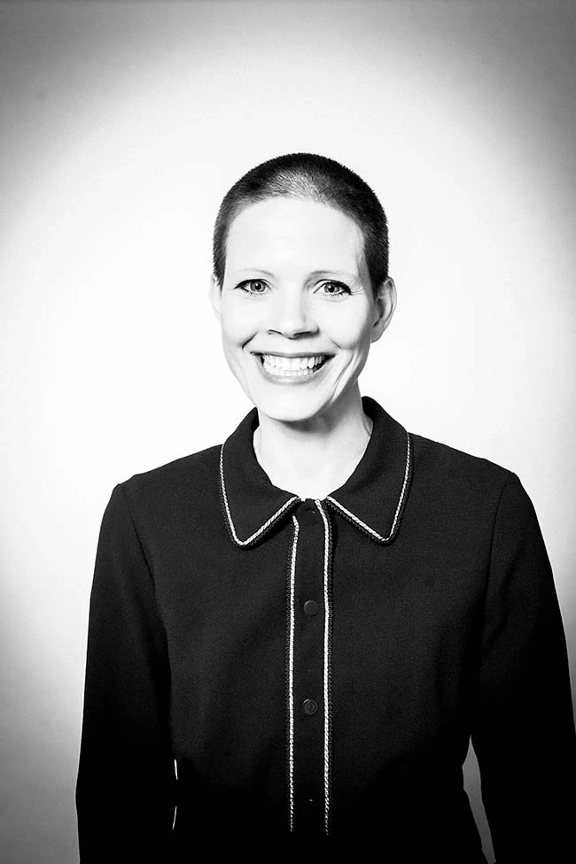 Ein Mitarbeiterfoto in schwarz-weiß, welches eine Frau fröhlich lächelnd abbildet. 