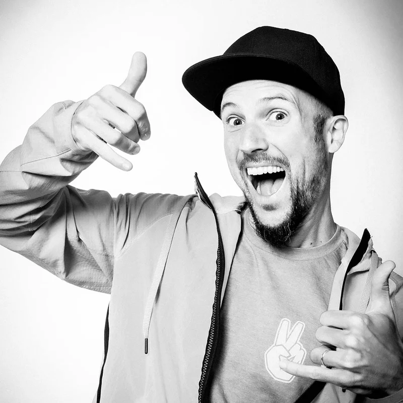 Ein Mann mit Kappe lächelt spaßig in die Kamera einer Fotobox und zeigt dabei einen Daumen hoch.